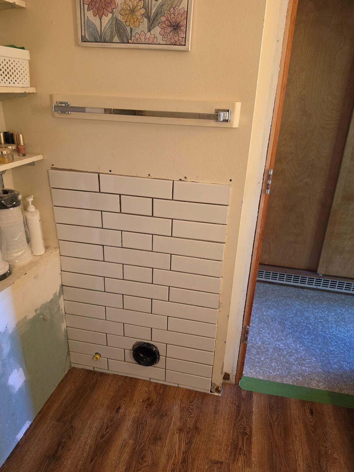 Bathroom with new white subway tile wall and wood-look flooring